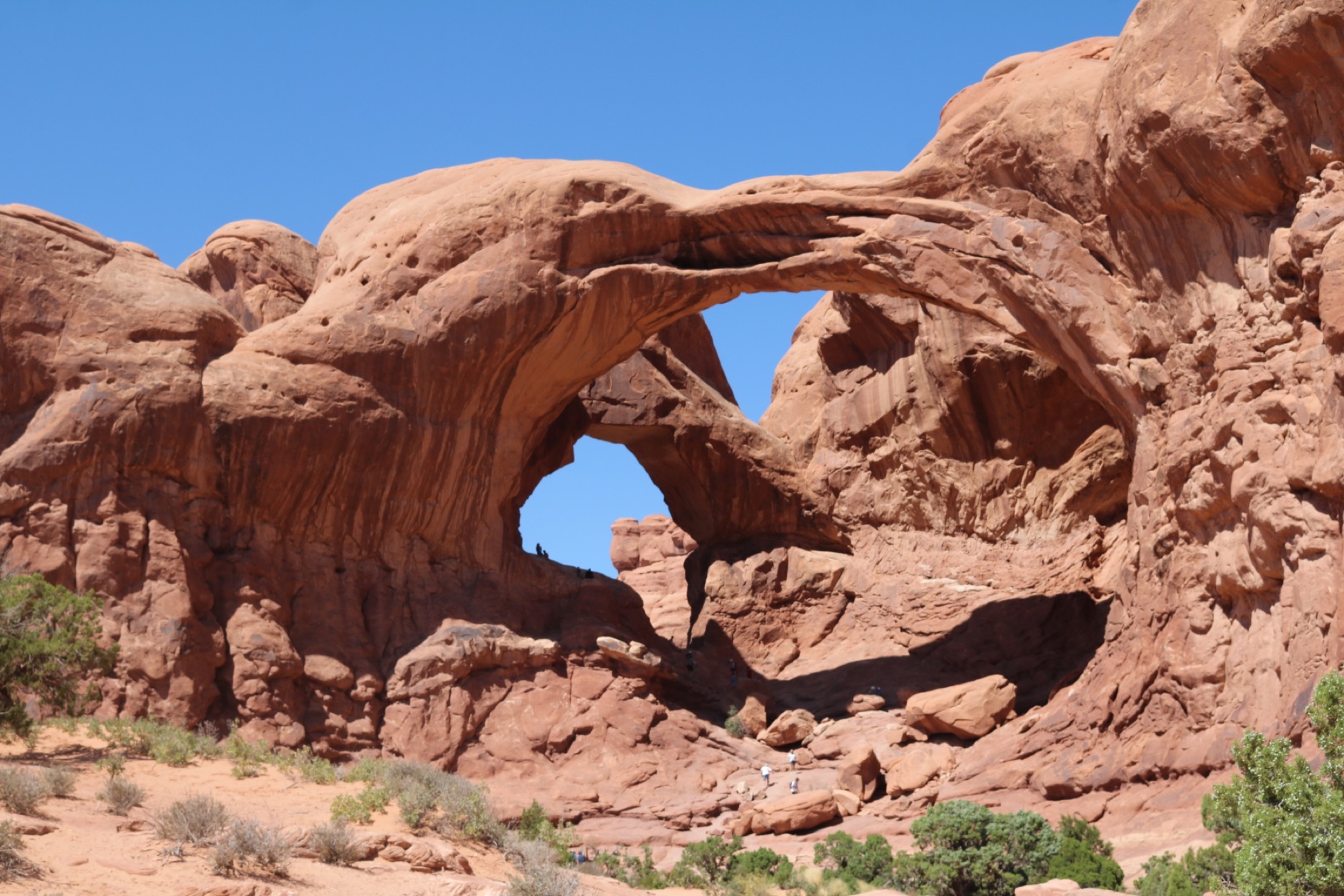 Layered red sandstone arches under blue sky