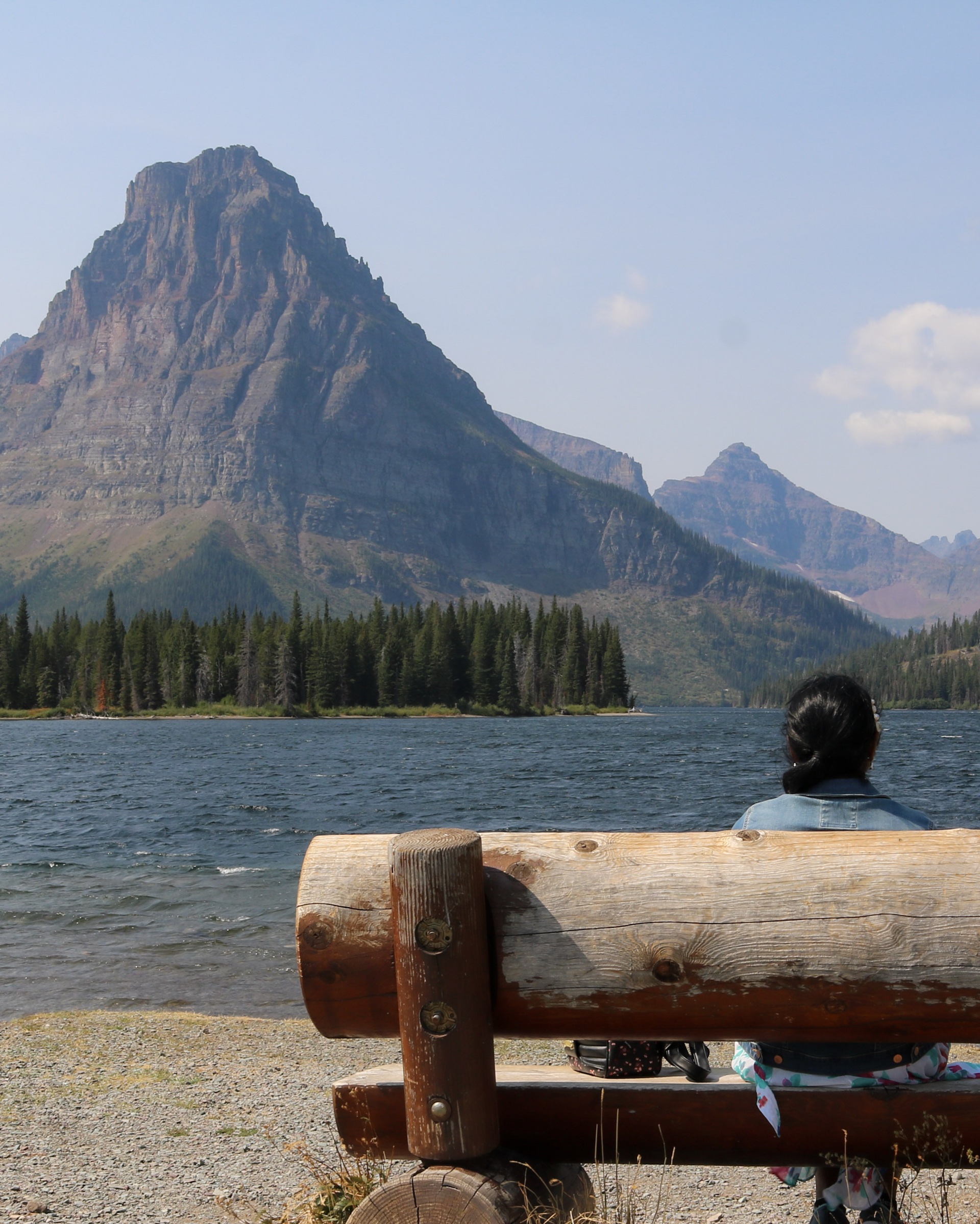 A traveler beside an alpine lake and mountains in Glacier National Park