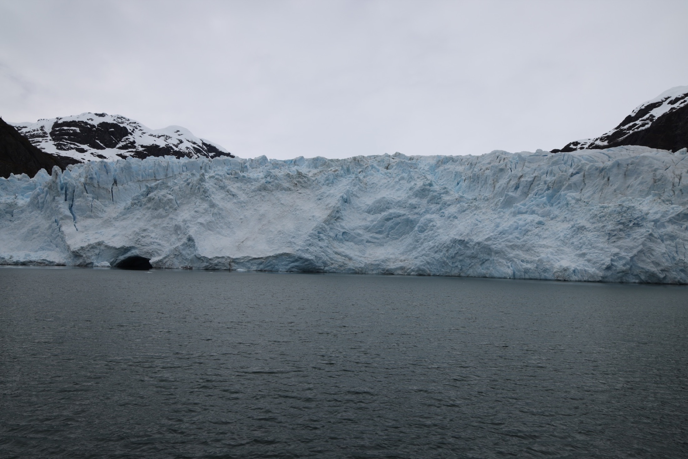 A wide tidewater glacier meeting the water along the Kenai Fjords coast