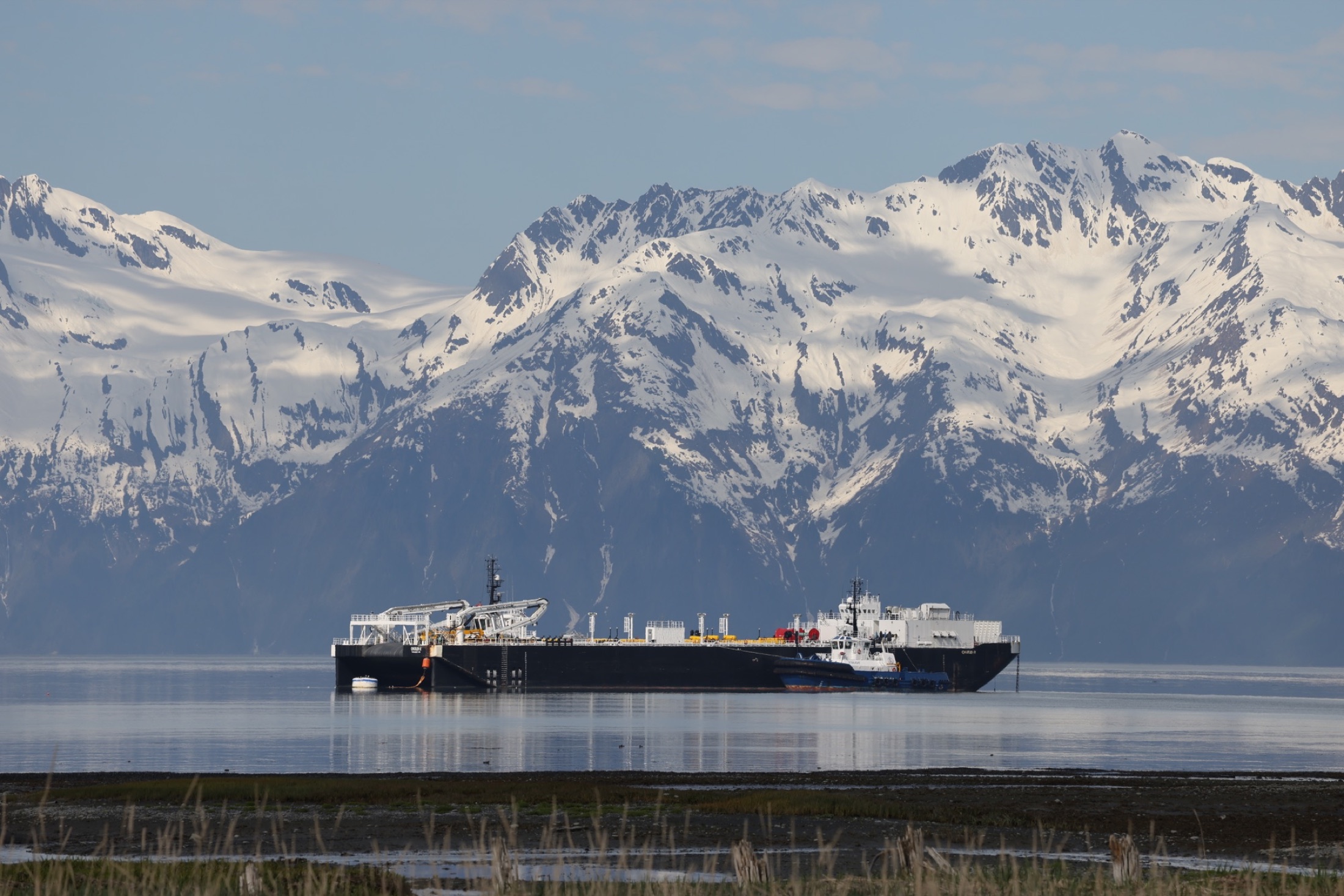 Harbor vessel on calm water beneath the snow-covered mountains near Valdez
